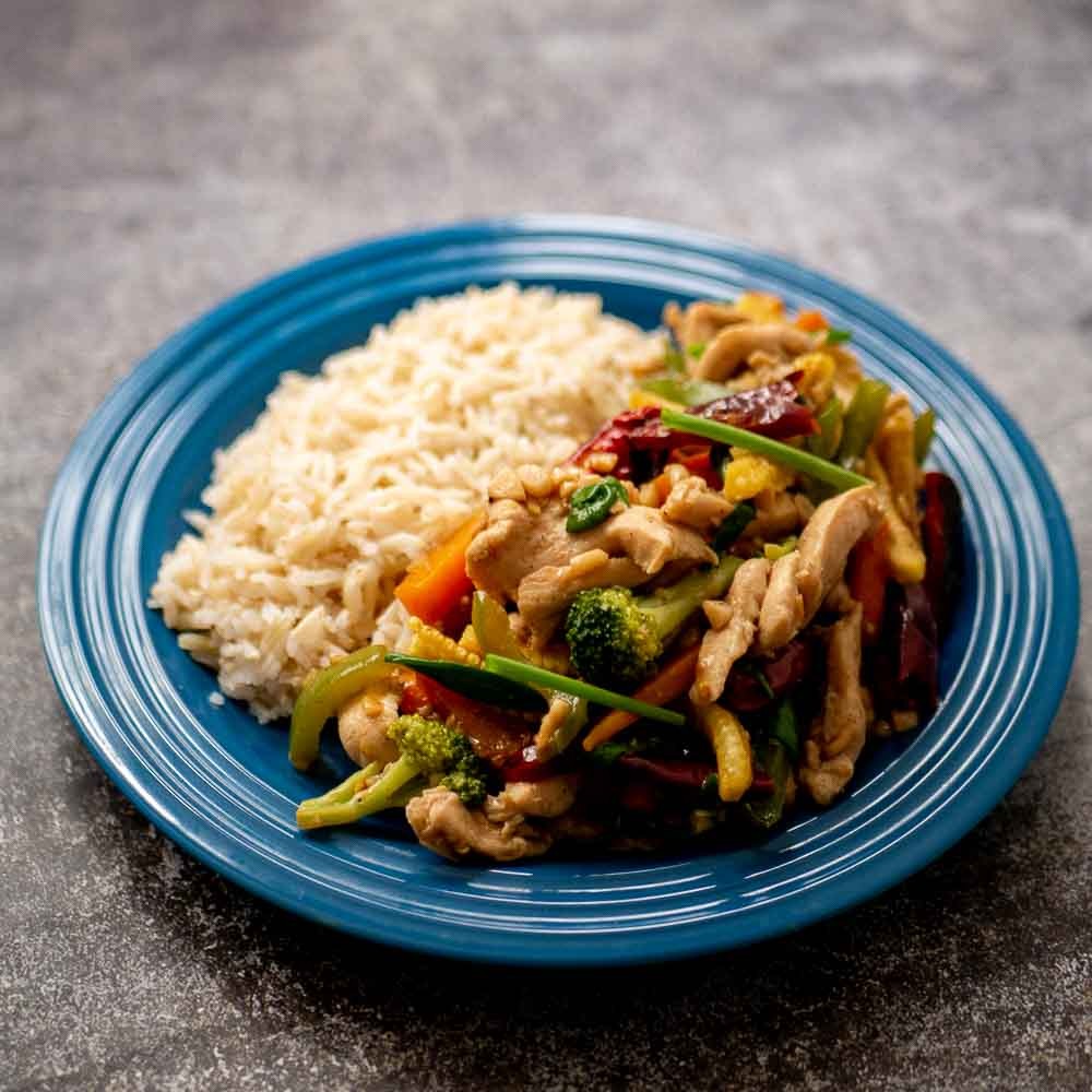 chicken stir-fry with brown rice in a wok, vibrant vegetables