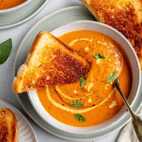 Rich creamy tomato soup with crusty golden bread for dipping, cozy setting