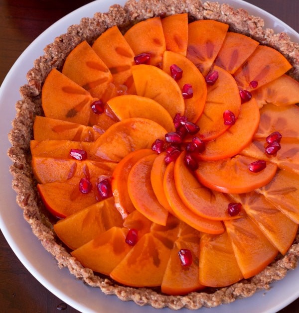 persimmon pecan praline tart with a slice cut out, showcasing the layers