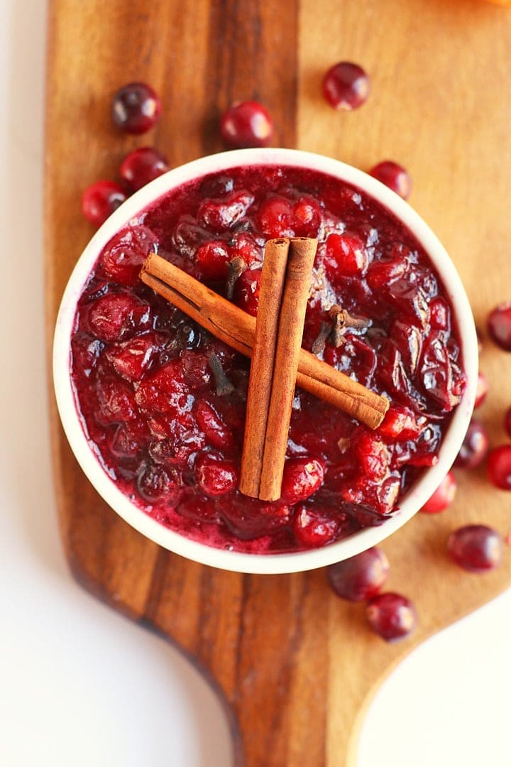 Homemade cranberry sauce with cinnamon sticks, orange zest, and star anise on a rustic background