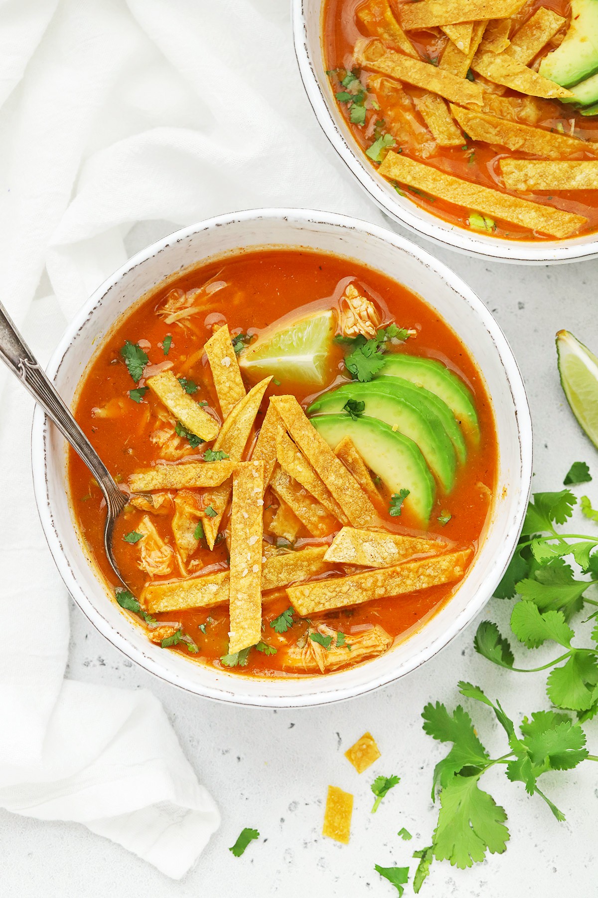 bowl of chicken tortilla soup topped with avocado and tortilla strips