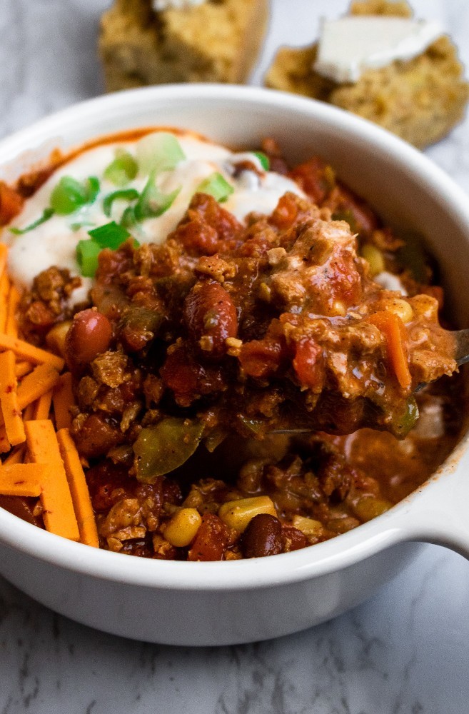 hearty bowl of vegan chili with TVP and toppings