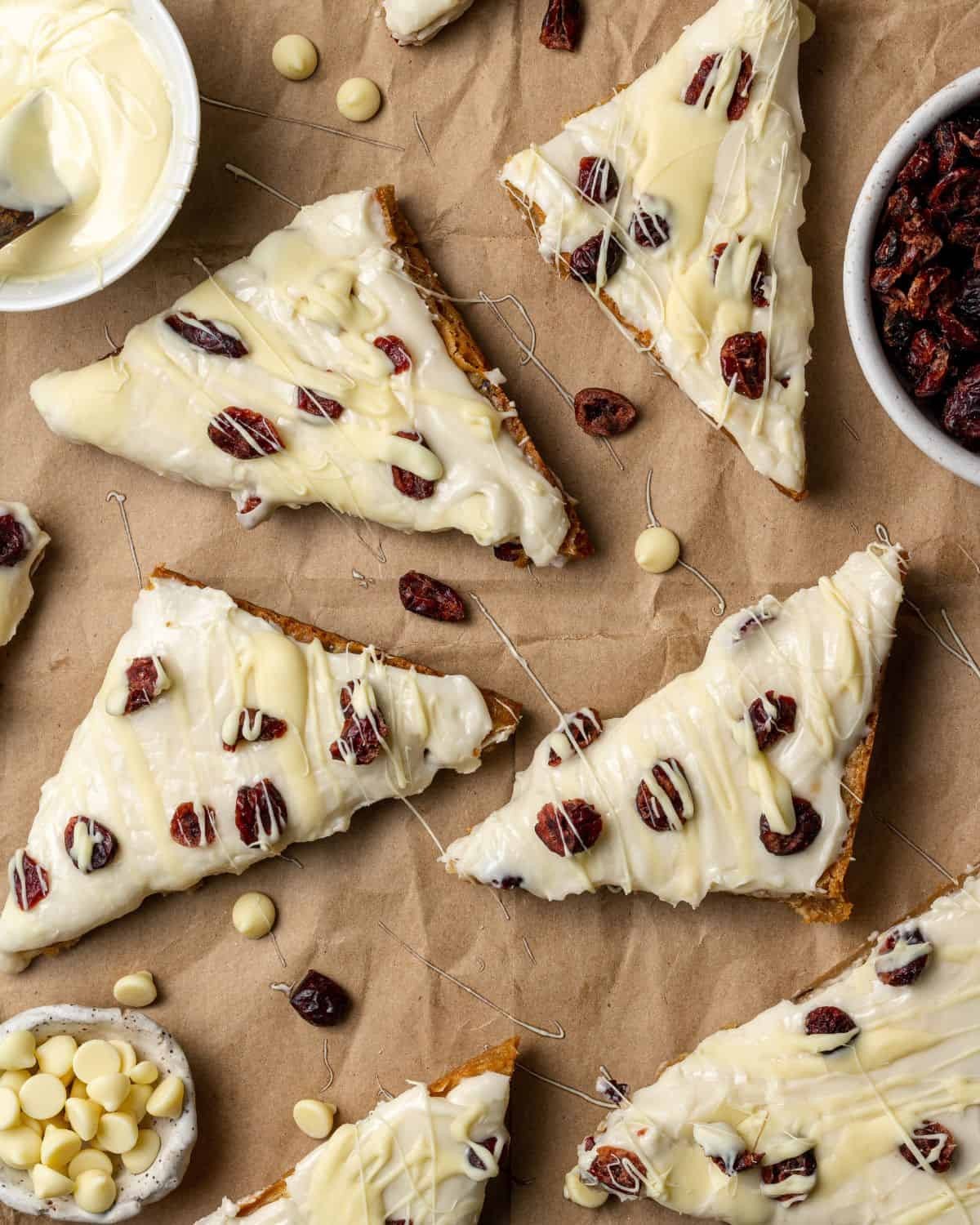 homemade cranberry bliss bars with white chocolate frosting and dried cranberries on a cooling rack, cozy kitchen setting