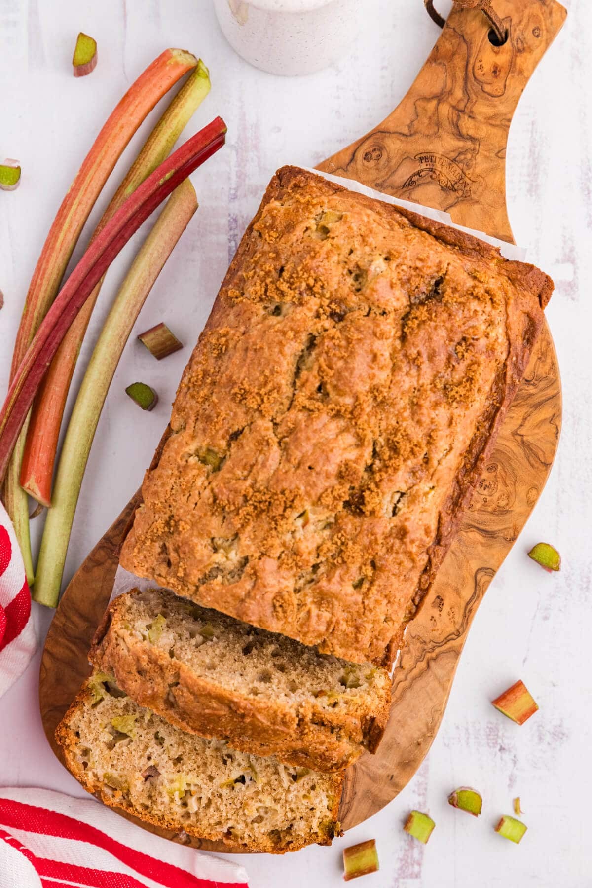 Rhubarb bread with a slice cut, displayed on a rustic wooden surface