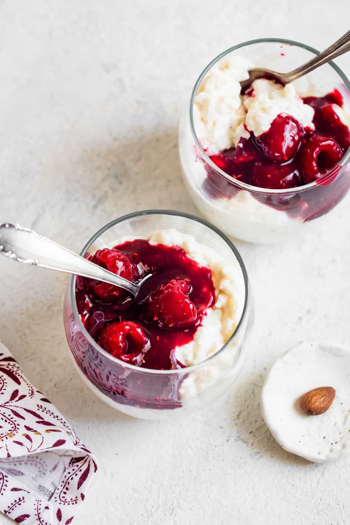 A bowl of creamy rice pudding with raspberries and rose petals on a light and airy background.