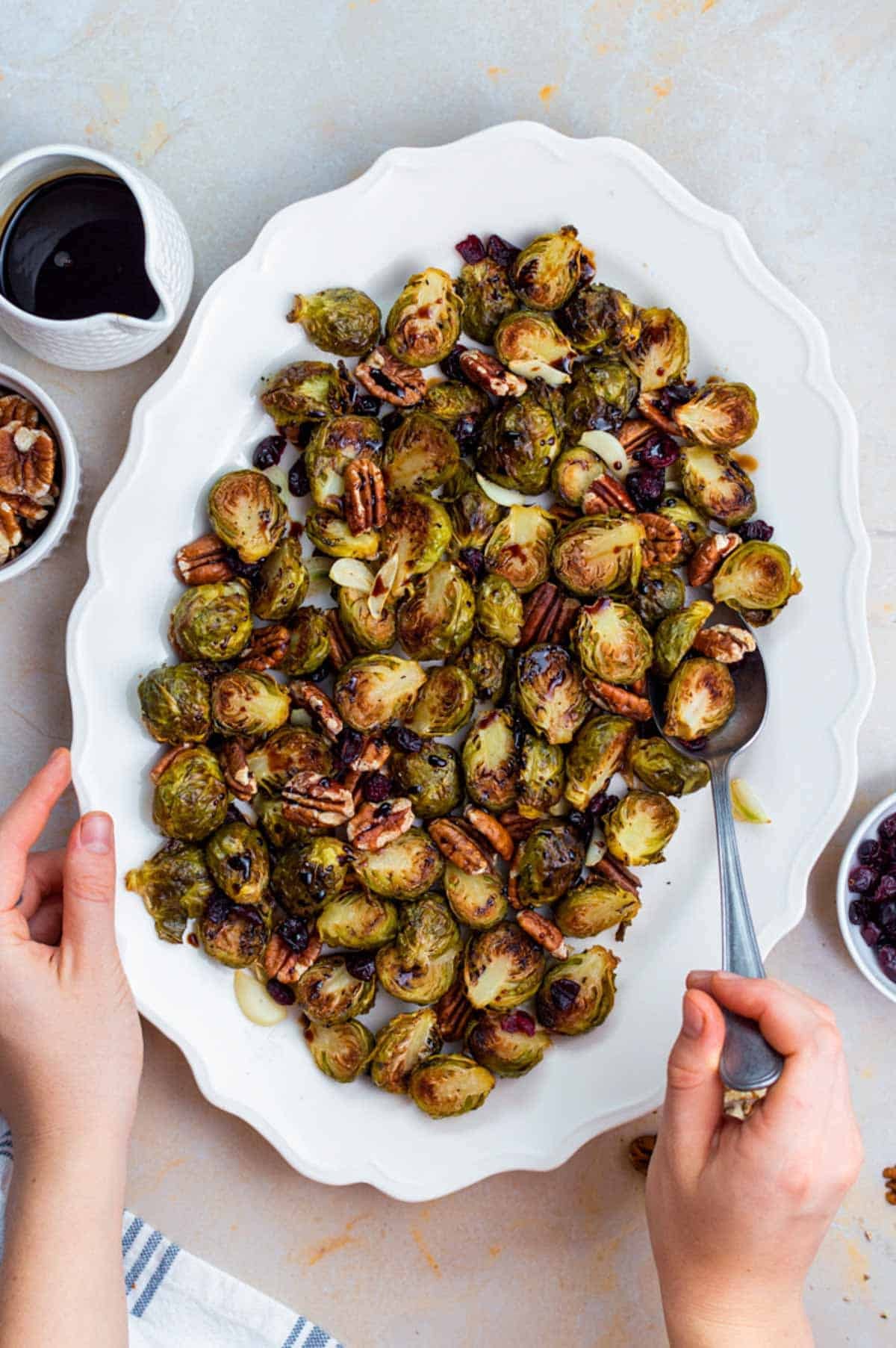 Crispy roasted Brussels sprouts with glistening balsamic glaze, close-up, on a white plate, rustic wooden table background, warm lighting