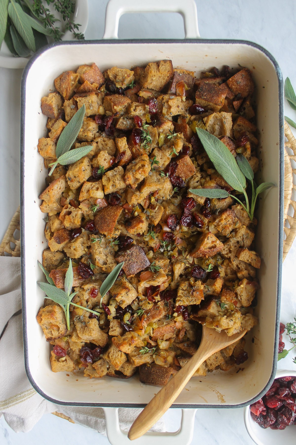 Thanksgiving maple cranberry stuffing in a rustic serving dish, garnished with fresh sage and cranberries