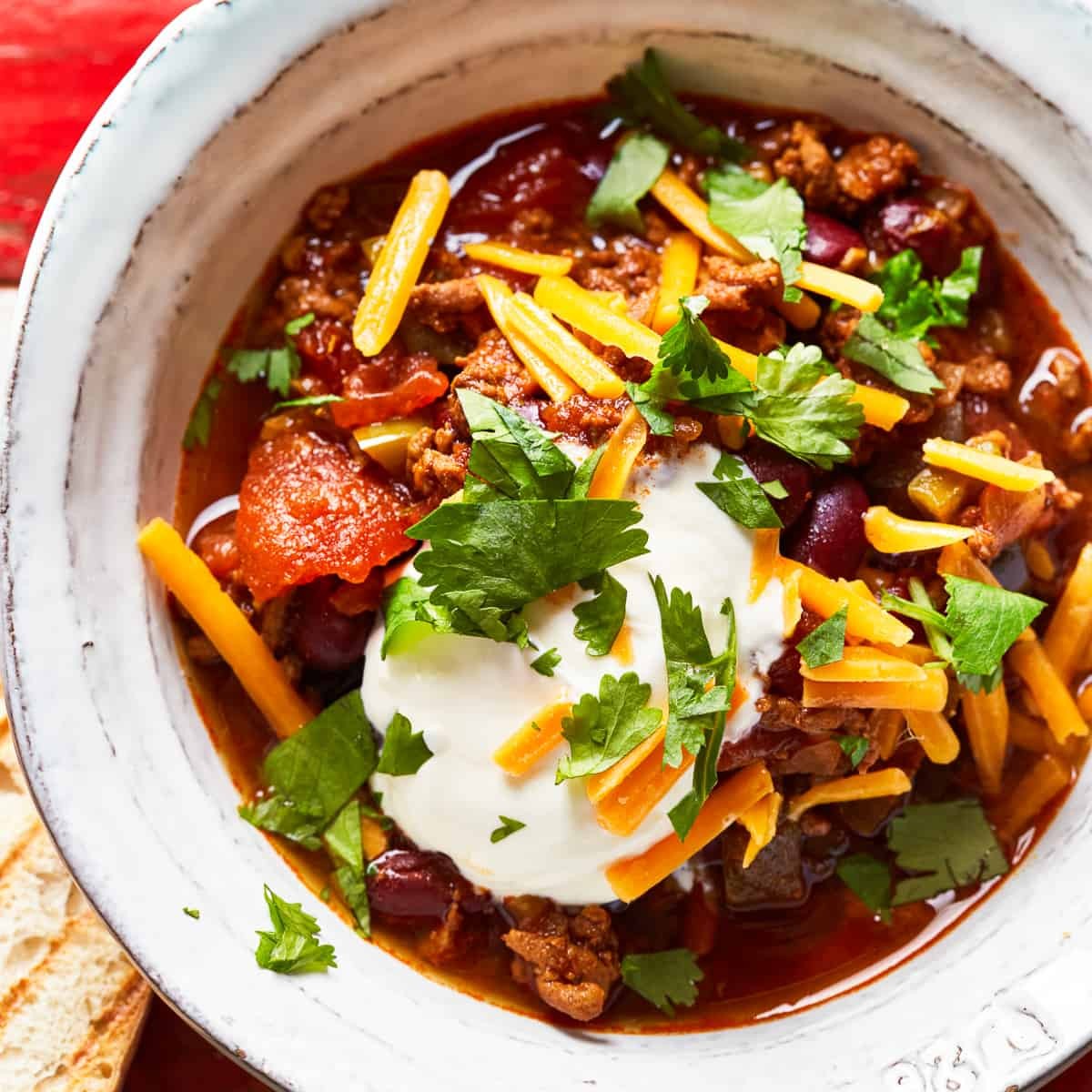 Vibrant close-up of a bubbling chili-loaded beef skillet, garnished with fresh cilantro and a dollop of sour cream, ready to serve.