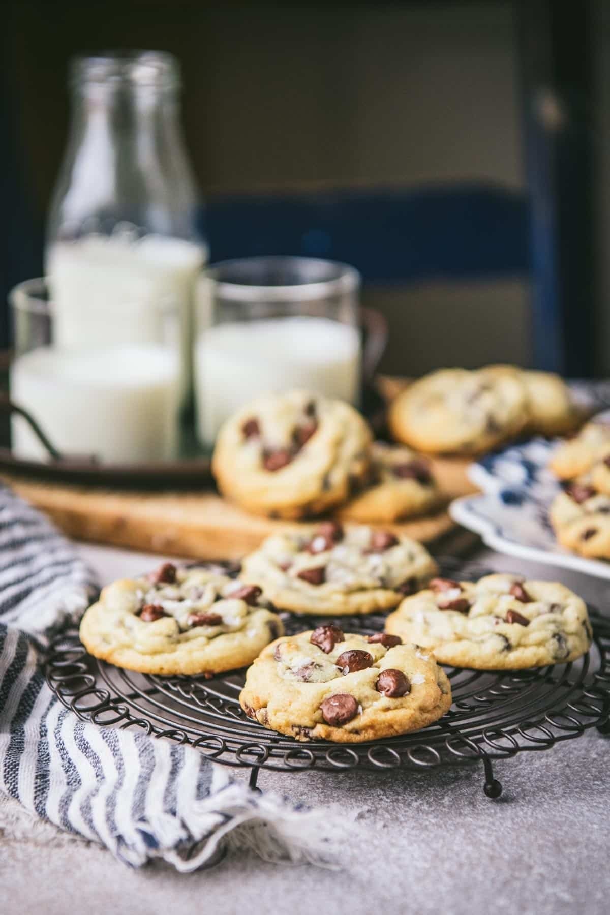 freshly baked sea salt chocolate chip cookies on a cooling rack with a glass of milk
