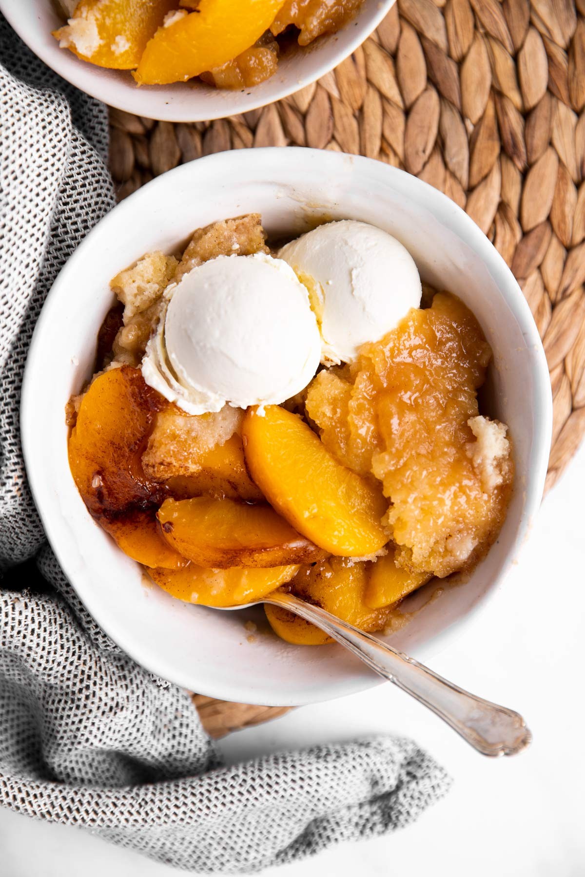 overhead shot of a freshly baked caramel swirl peach cobbler with a scoop of vanilla ice cream