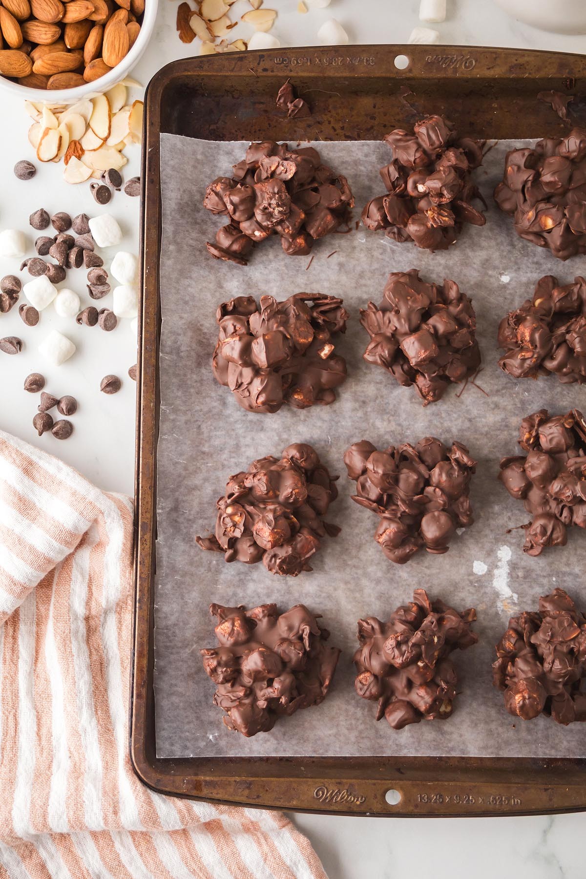 overhead shot of rocky road cookie dough bites on a plate, surrounded by ingredients like chocolate chips, marshmallows, and almonds