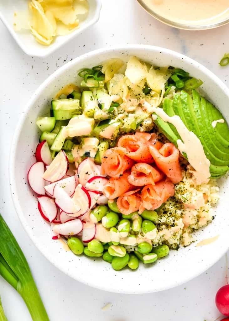 Spicy salmon avocado bento box with nori seaweed rice, edamame, and pickled ginger