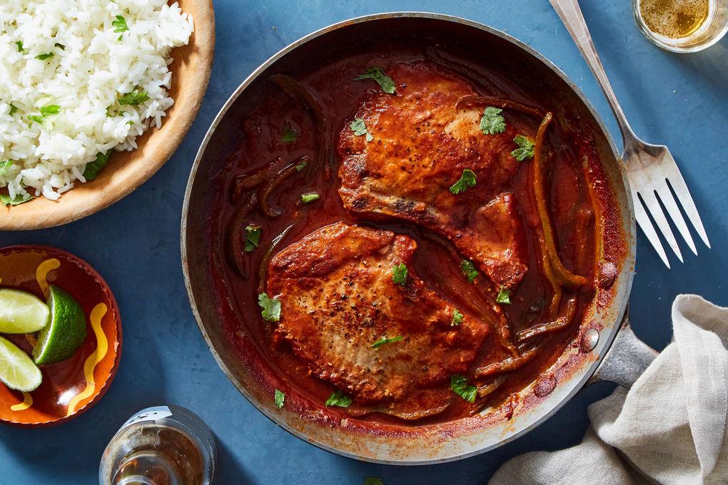 Adobo marinated pork chops served with cilantro lime rice on a rustic wooden table